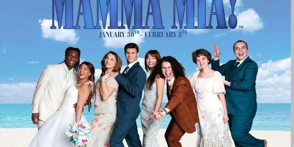Cast of Mamma Mia! posing on a beach for the musical's promotion.