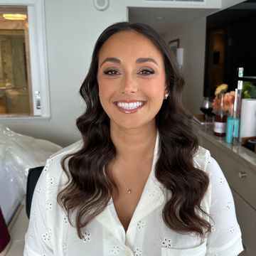 Smiling woman with wavy hair in a white blouse.