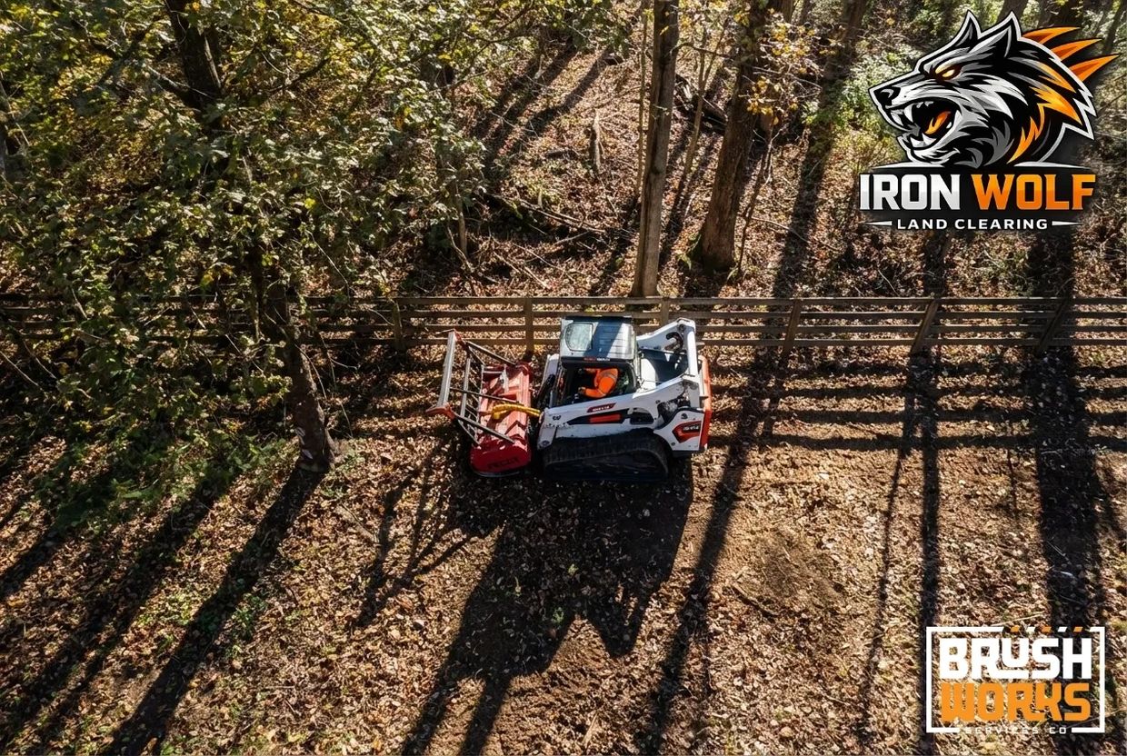 A compact bulldozer clearing land in a forested area with Iron Wolf logo.