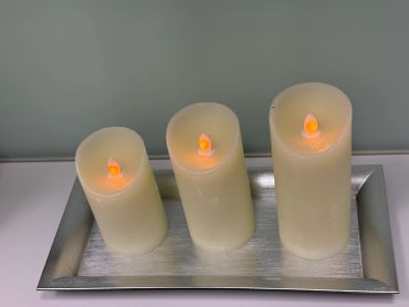 Three LED candles on a silver tray.