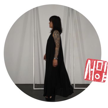 Woman in black dress with lace sleeves standing in profile.