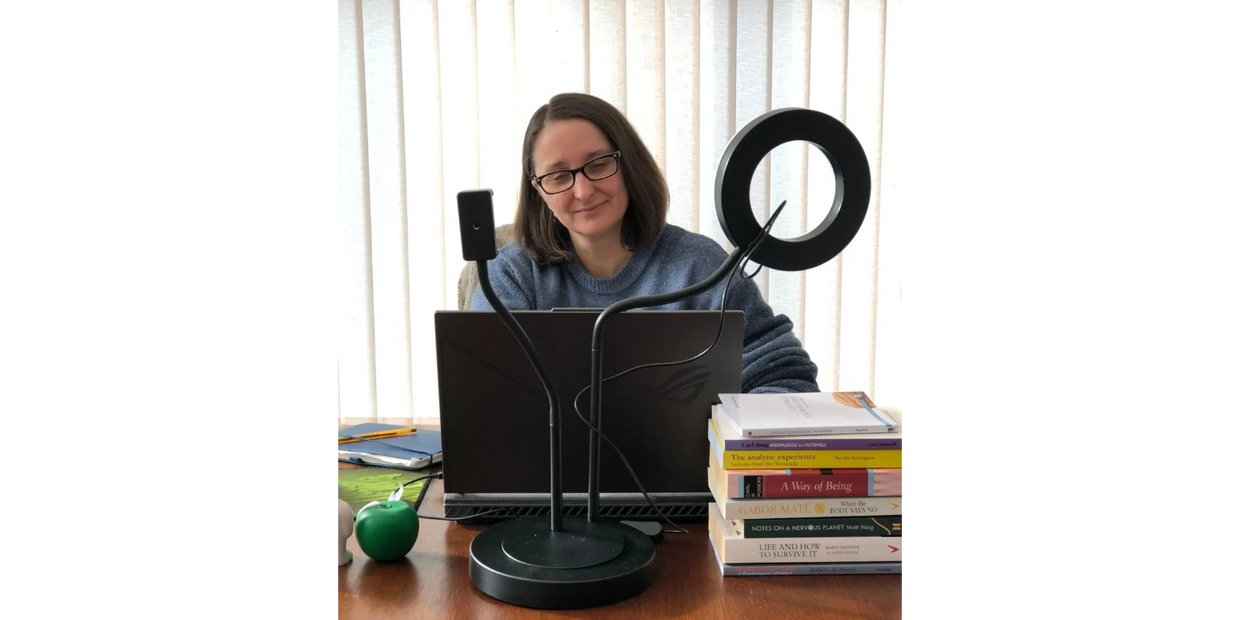 Me at my desk working on my laptop. A stack of books on one side and some stress balls on the other.