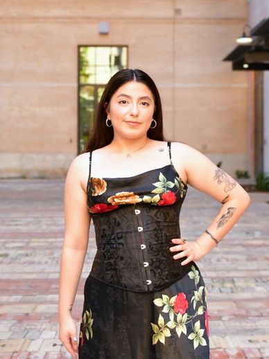 Woman in floral dress and corset posing outdoors.