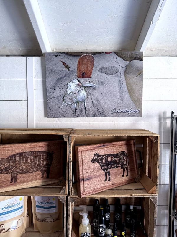 Rustic wooden crates display meat cut charts and condiments beneath a framed beach-themed photo.
