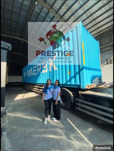 Two women standing in front of a blue shipping container at a warehouse.