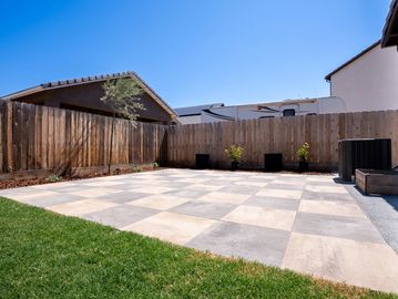 Backyard with tiled patio and wooden fence.