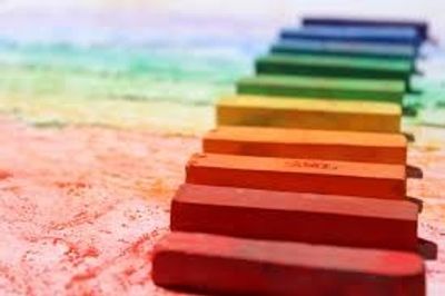 Colored chalk sticks arranged in a row forming a rainbow gradient.