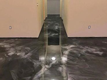 Shiny black and gray polished concrete floor in a hallway under construction.