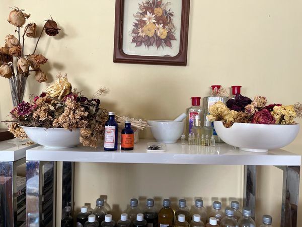 Shelf with bowls with dry flowers, bottles of rose water and lavender essential oil from Grasse, pes