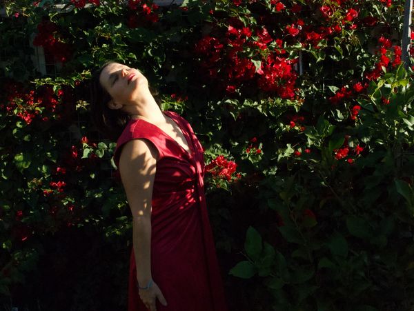 Image of Ana posing in a bougainvillea colour dress next to the bougainvilleas