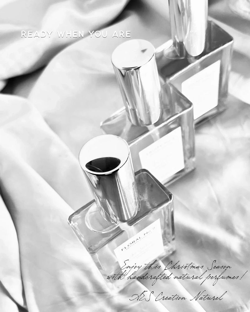 Black and White image of 3 rectangular spray perfume bottles looked from above with siilver caps.