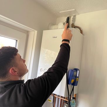 Technician adjusting a boiler unit with diagnostic tools.