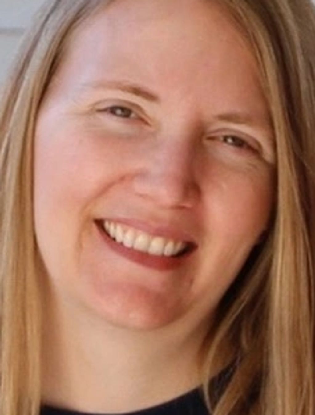 Close-up portrait of a smiling woman with blonde hair.