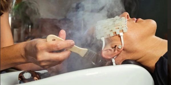 Person receiving a smoky hair treatment with a brush and a special head device.