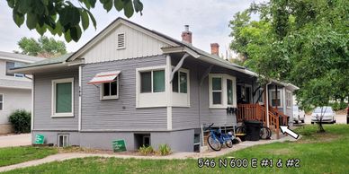 Gray residential house with a porch and green lawn.