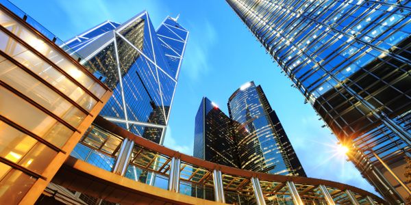 Looking up at modern skyscrapers against a clear blue sky.
