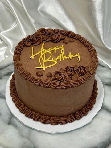 Chocolate birthday cake with yellow "Happy Birthday" icing.