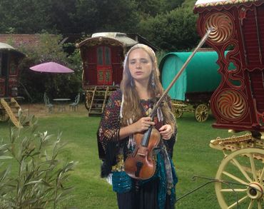 Gypsy Dawn in a gypsy camp holding her violin. 