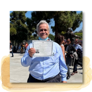 A man holding a US Citizenship certificate and smiling.