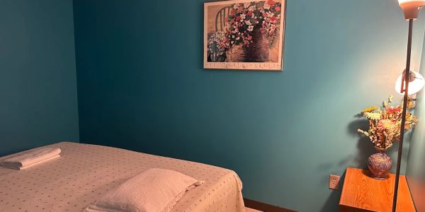 Cozy massage room with calming teal walls and floral decor.
