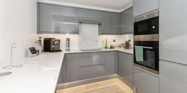 Modern kitchen with glossy grey cabinets and white countertops.