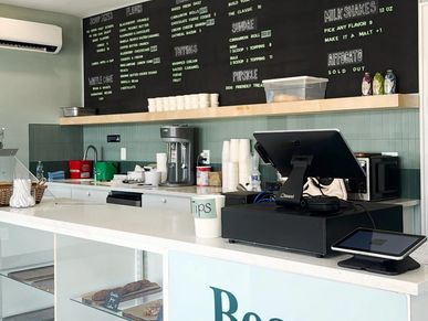 Modern cafe counter with menu on chalkboard and tip jar.