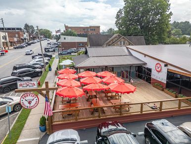 Outdoor dining area with red umbrellas at Fortz Pizza in a small town.