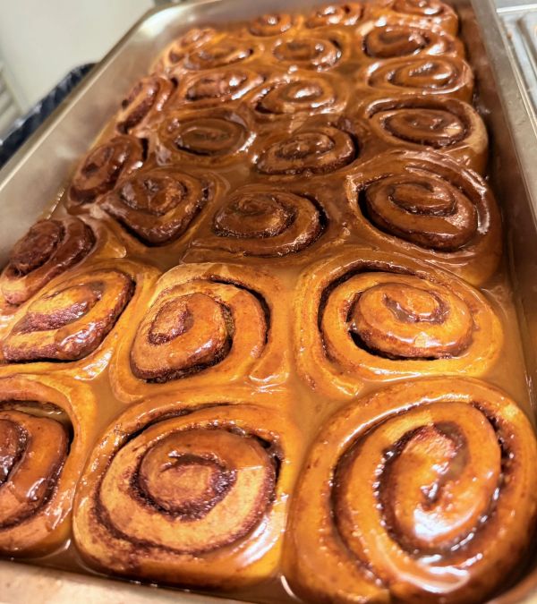 Tray of freshly baked cinnamon rolls with glaze.