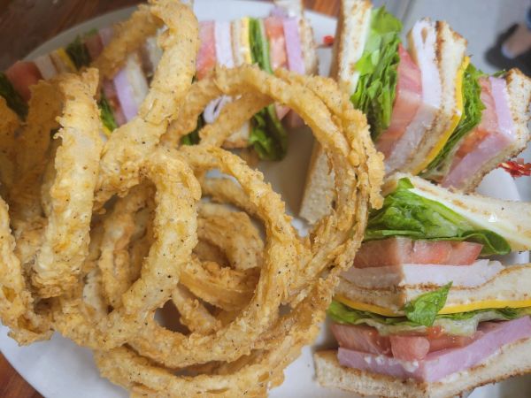 Plate with onion rings and club sandwiches.