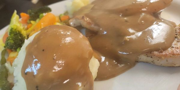 Mashed potatoes and chicken with gravy on a plate.