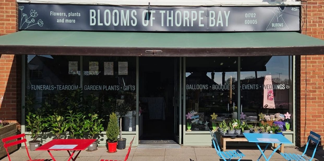 An image of the front of the shop including the shop sign, some tables for the tea room & the canopy