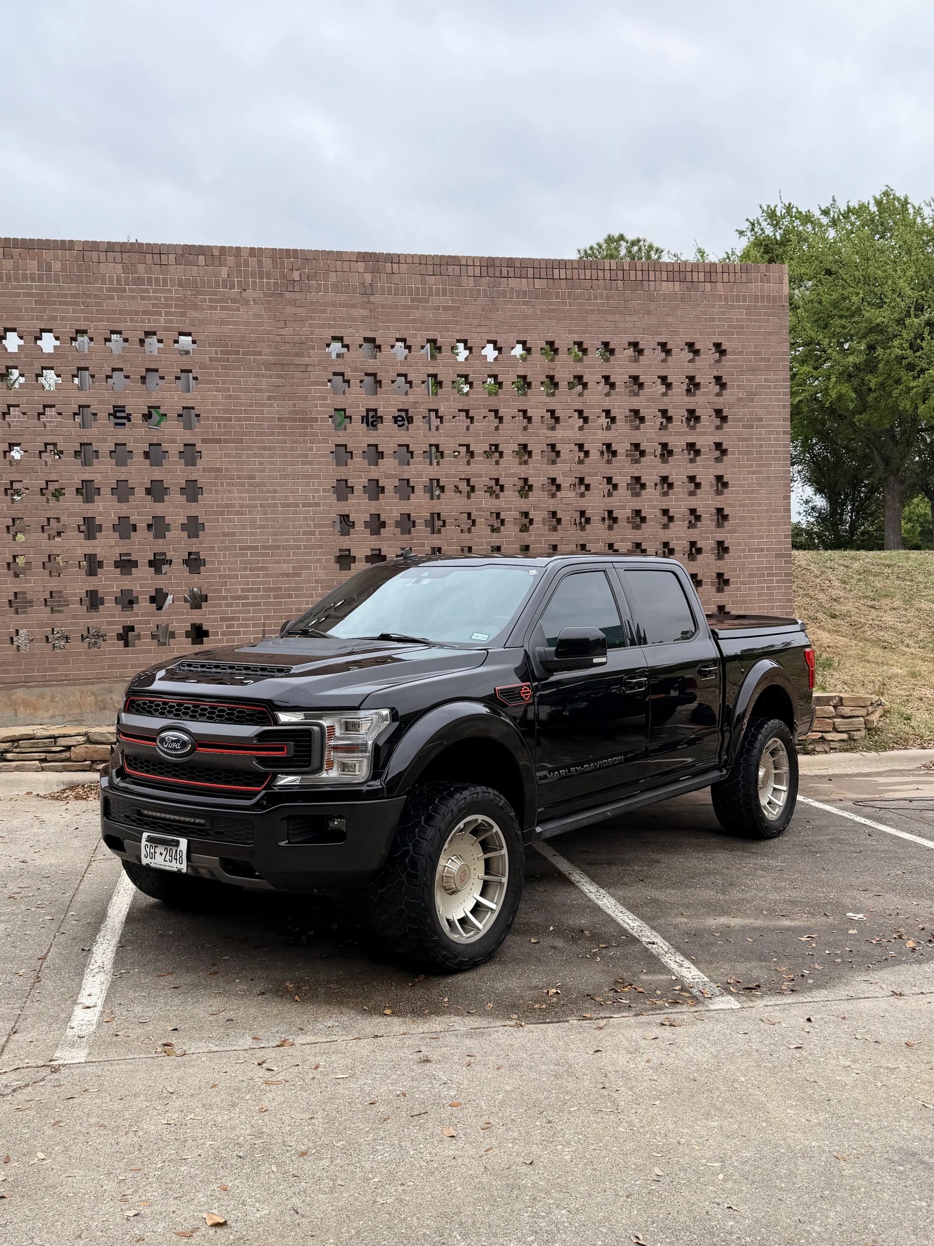 Black Ford Harley-Davidson truck parked by a brick wall.