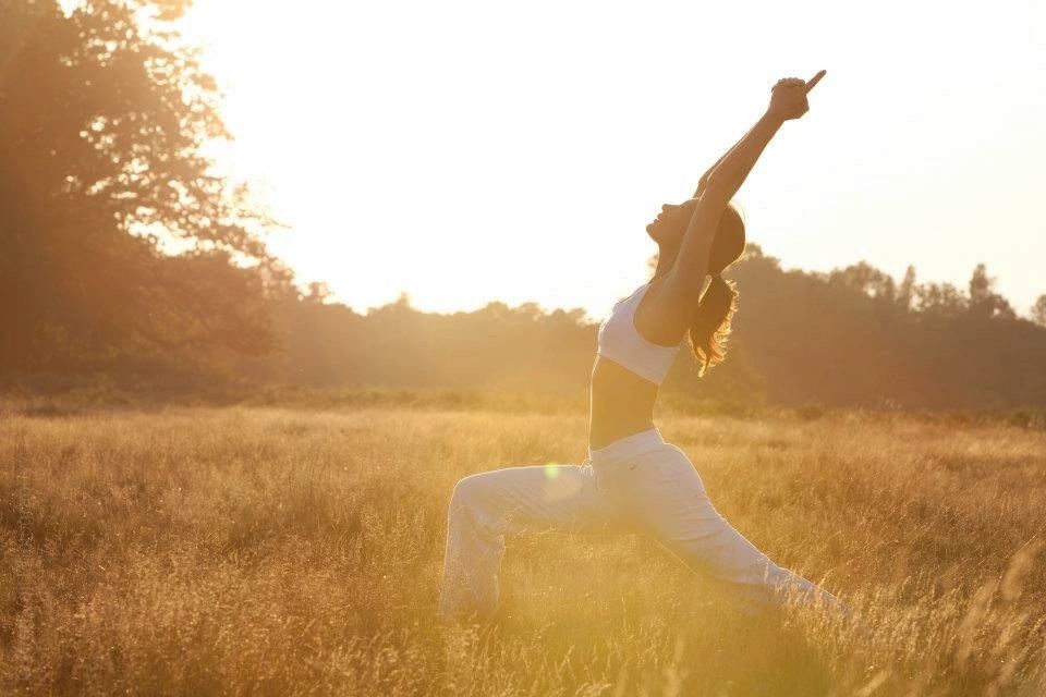 Beautiful curvy girl doing yoga in nature on a sunny summer sunset