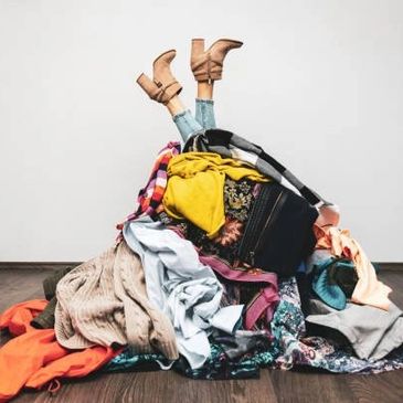 woman covered with pile of clothes. only her feet sticking out.