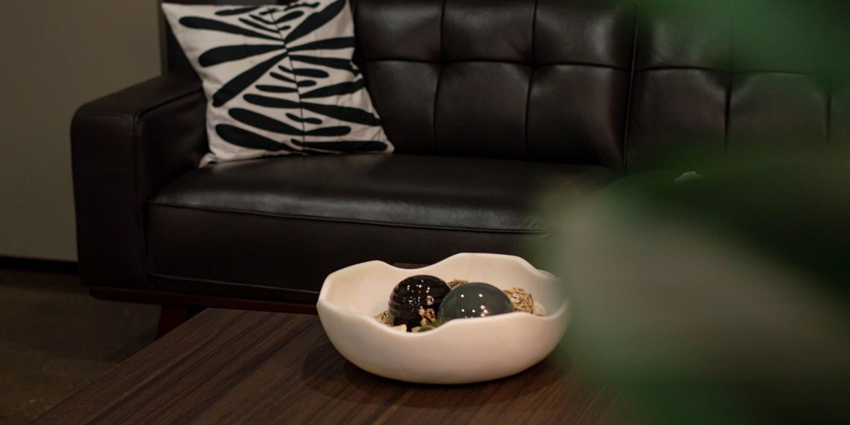 Modern living room with a black leather sofa and decorative bowl.