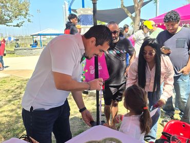 Man interacting with a young girl at an outdoor event booth.