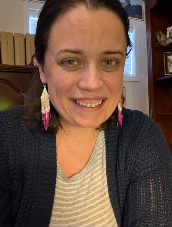 Woman smiling with beaded earrings.