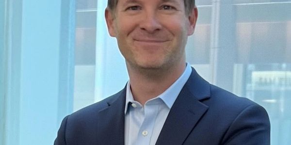 Confident man in navy suit with arms crossed, smiling.