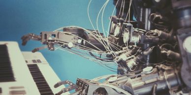 Mechanical robot playing a two tiered digital keyboard. Photo by Possessed Photography on Unsplash