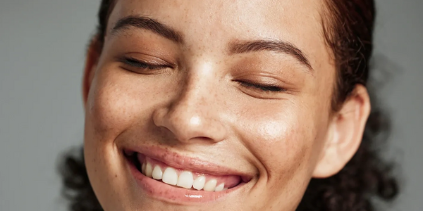 Close-up of a smiling woman with eyes closed and natural skin tone.