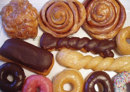 Assorted glazed and chocolate-covered donuts and pastries arranged on a tray.