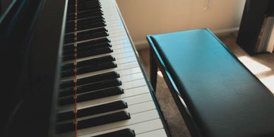 Up-close image of the piano keys and the piano bench on a high polish ebony upright piano