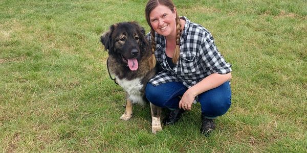 Lu kneeling down with a Caucasian Shepherd