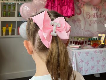 Girl with pink bow and number 1 clip at a birthday party.