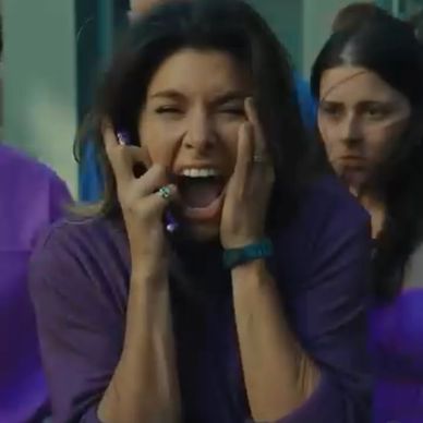 Woman screaming with hands on face, others in background.