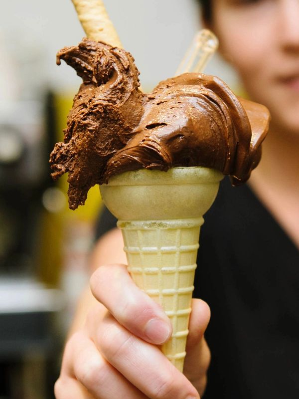 Hand holding a chocolate ice cream cone.