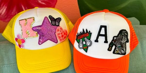 Two colorful caps with decorative patches and letters K and A.