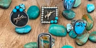 Turquoise jewelry and polished stones arranged on a wooden surface.