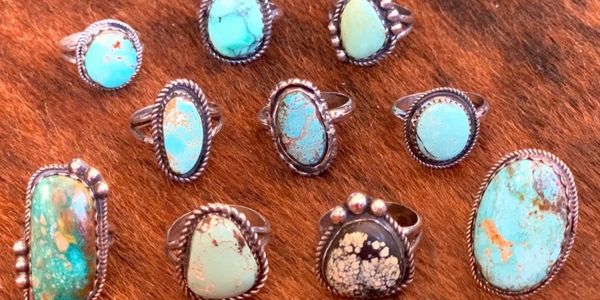 Collection of turquoise rings on a brown textured surface.