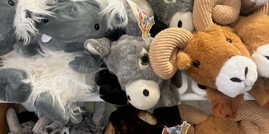 A group of animal plush toys including a ram and a donkey on display.